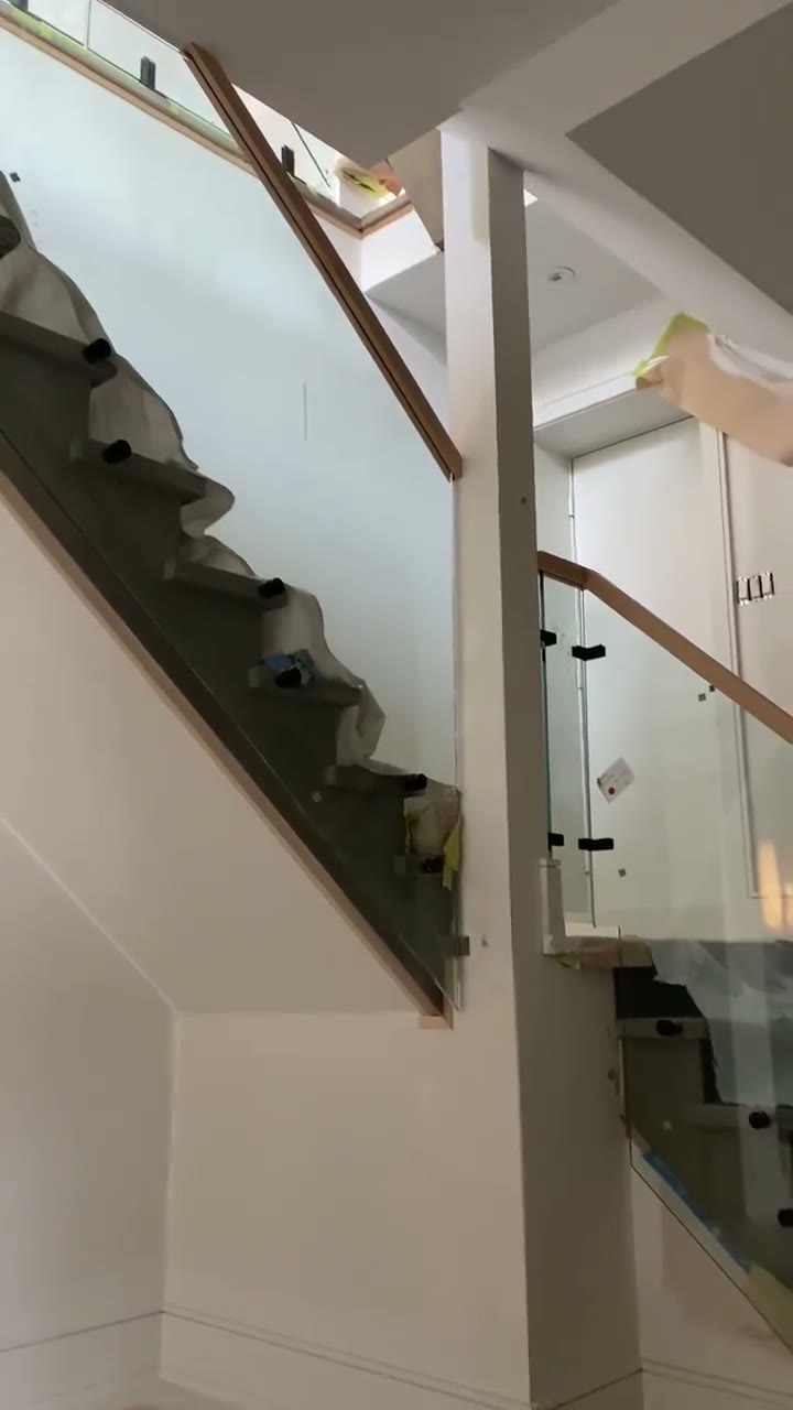 Glass stair railing with white-oak handrail along an open-riser staircase